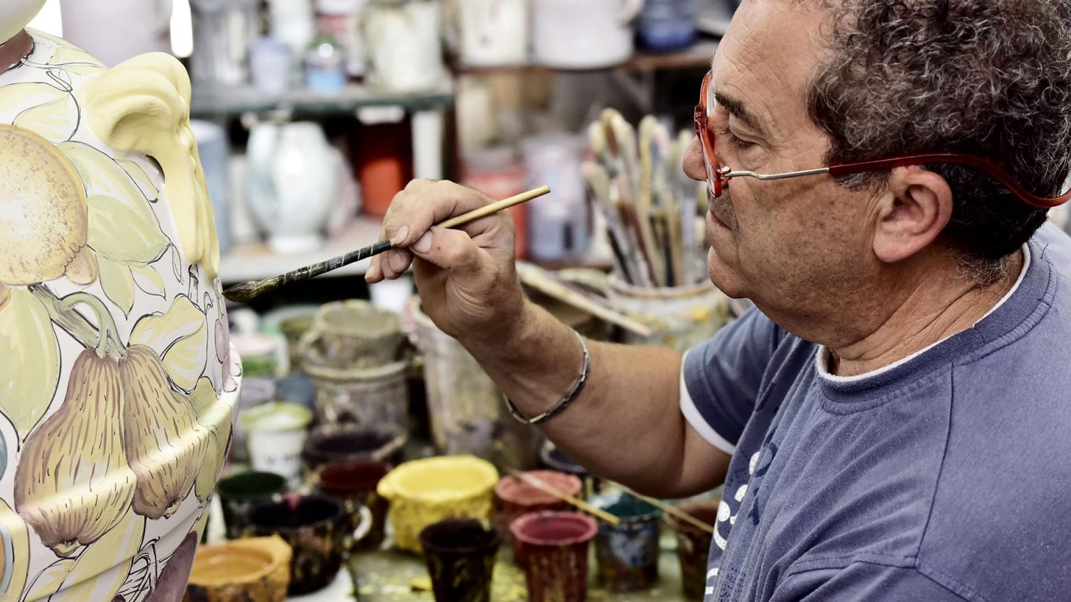tuscan artisan painting a sketch on a pot